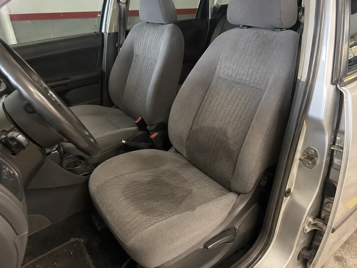 asiento del conductor de tela gris con mancha oscura de sudor y grasa