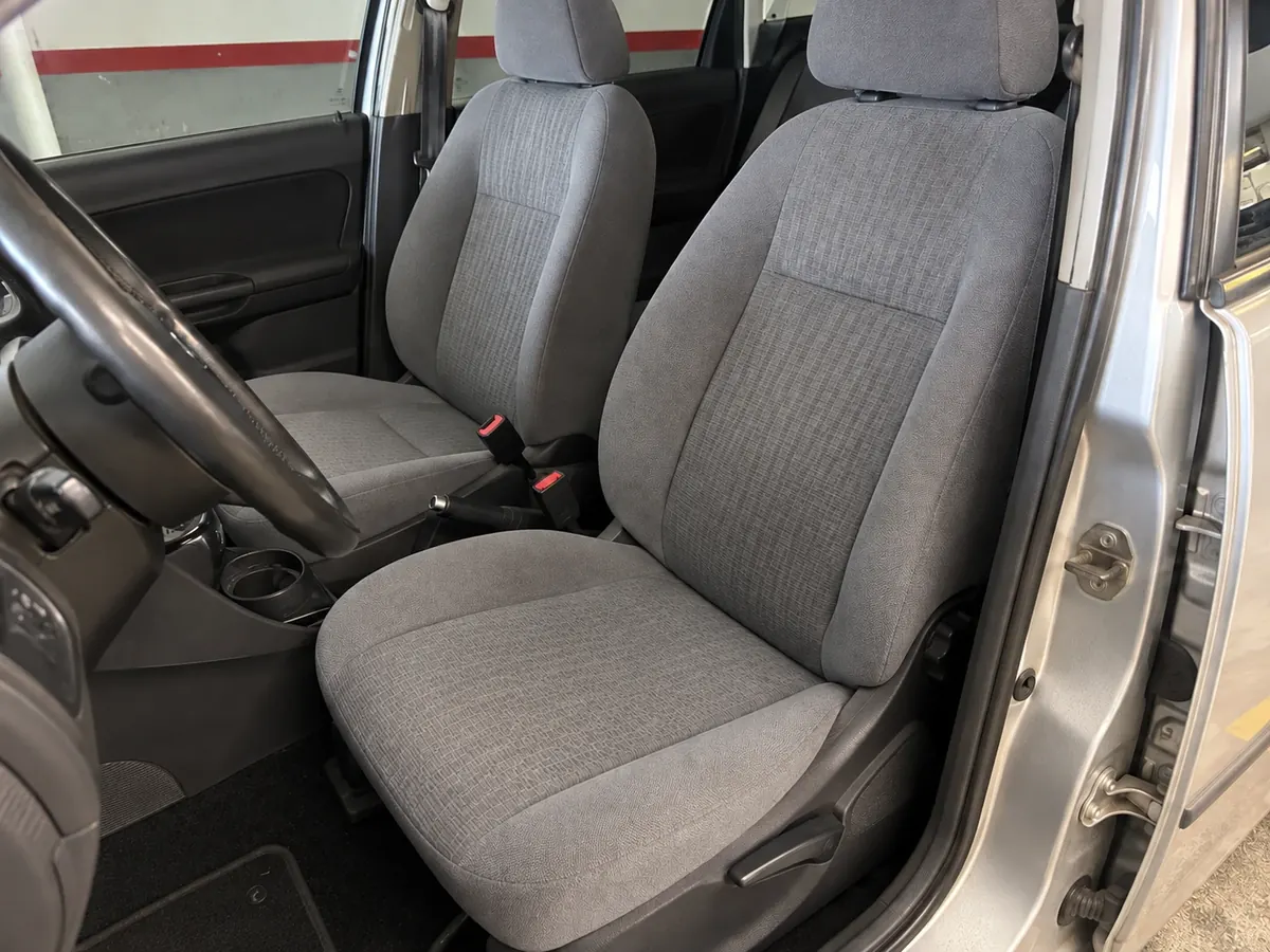 Resultado de limpieza: asiento del conductor de tela gris con mancha oscura de sudor y grasa